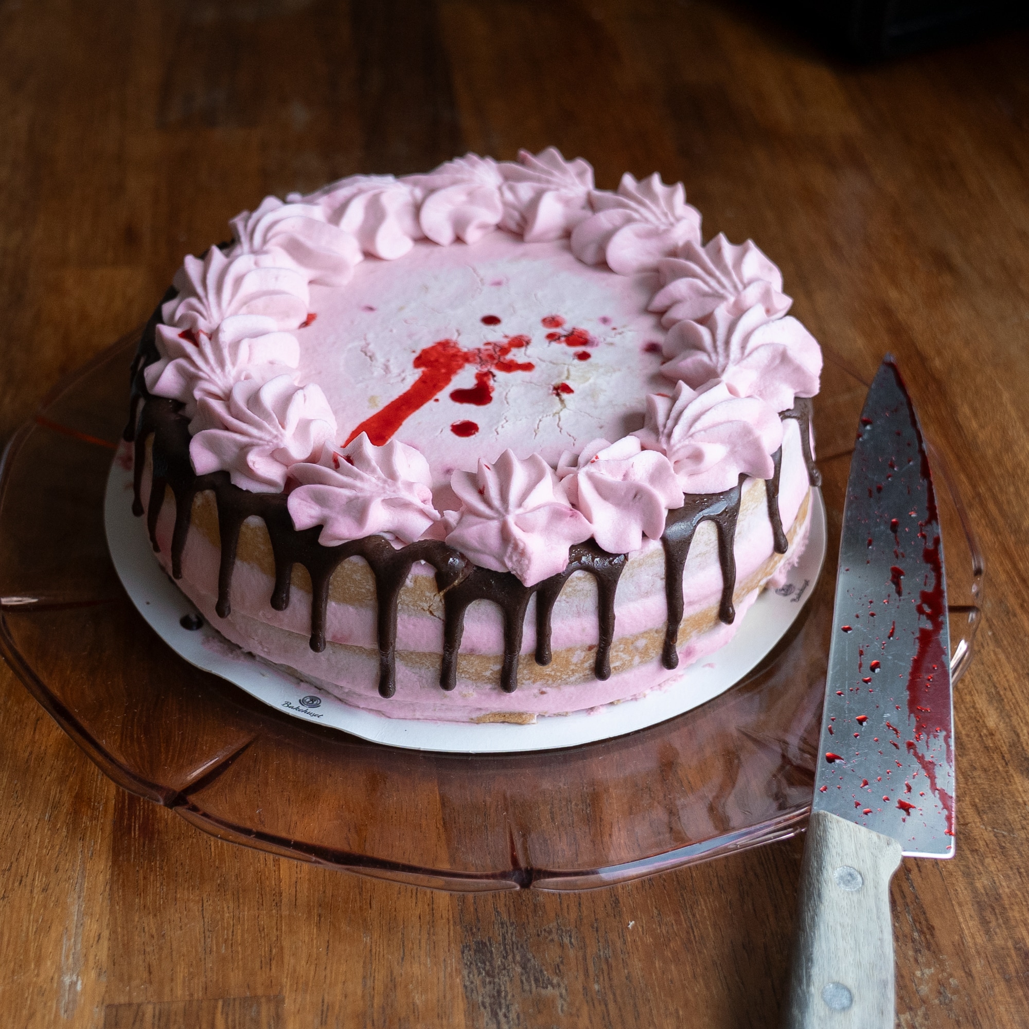 en blodig kniv og en pyntet kake med blodspor i et kjøkken