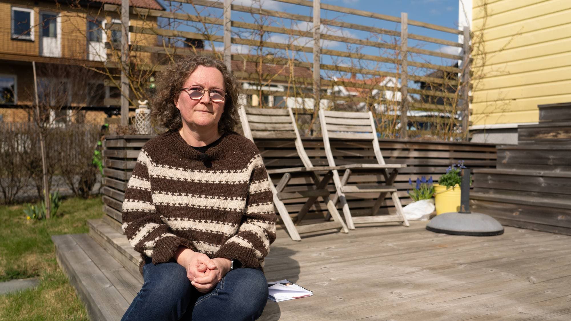 Kvinne med krøller og brunt hår på en terrasse