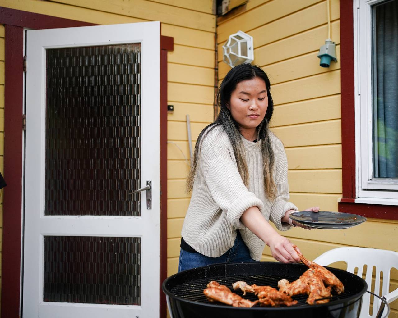 Ann-Hilde putter kotelettene på grillen.