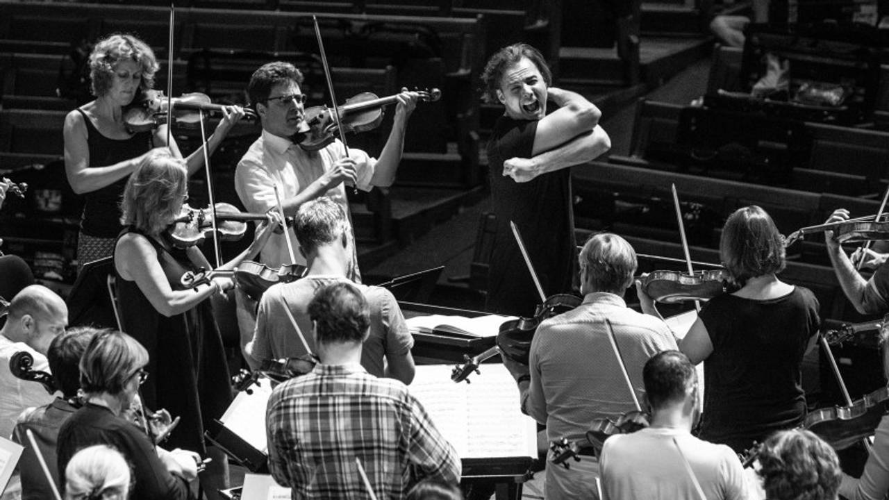 Teodor Currentzis intenst diregierende med musikere stående rundt seg