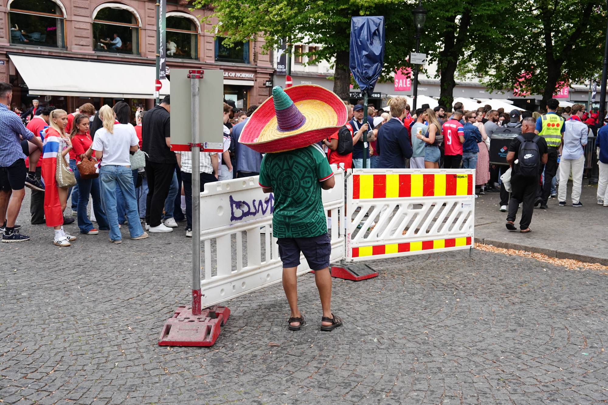 En person med en stor sombrero står ved siden av den lange køen til Spikersuppa. 