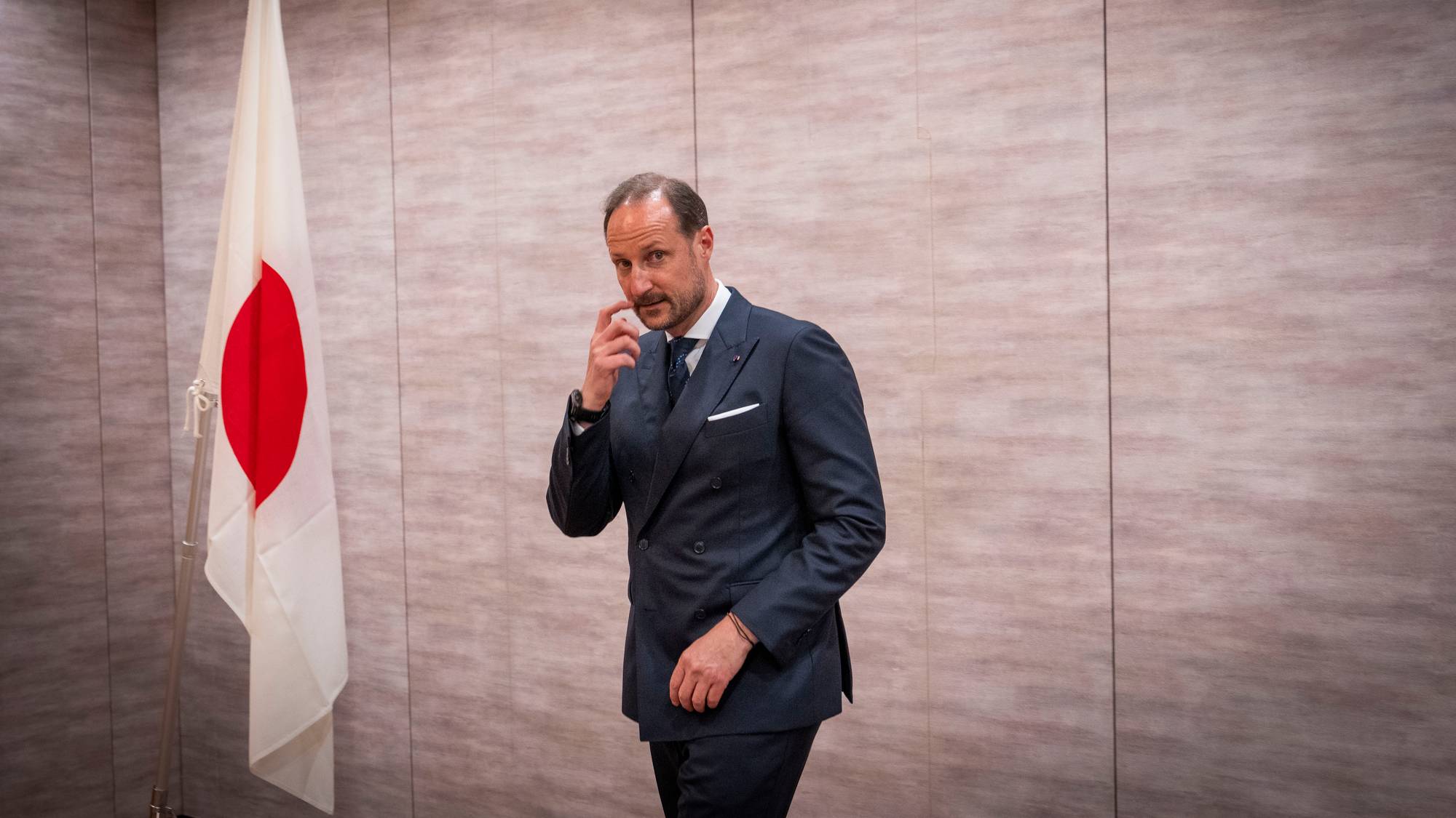 Kronprins Haakon står ved siden av et japansk flagg i Tokyo