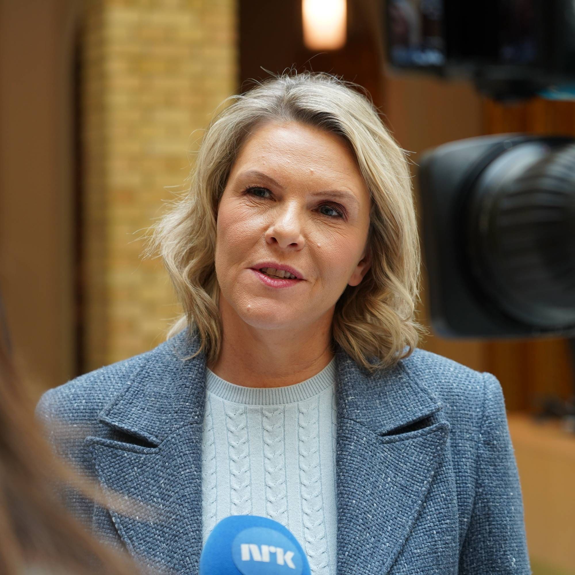 Sylvi Listhaug foran et kamera og en NRK-mikrofon