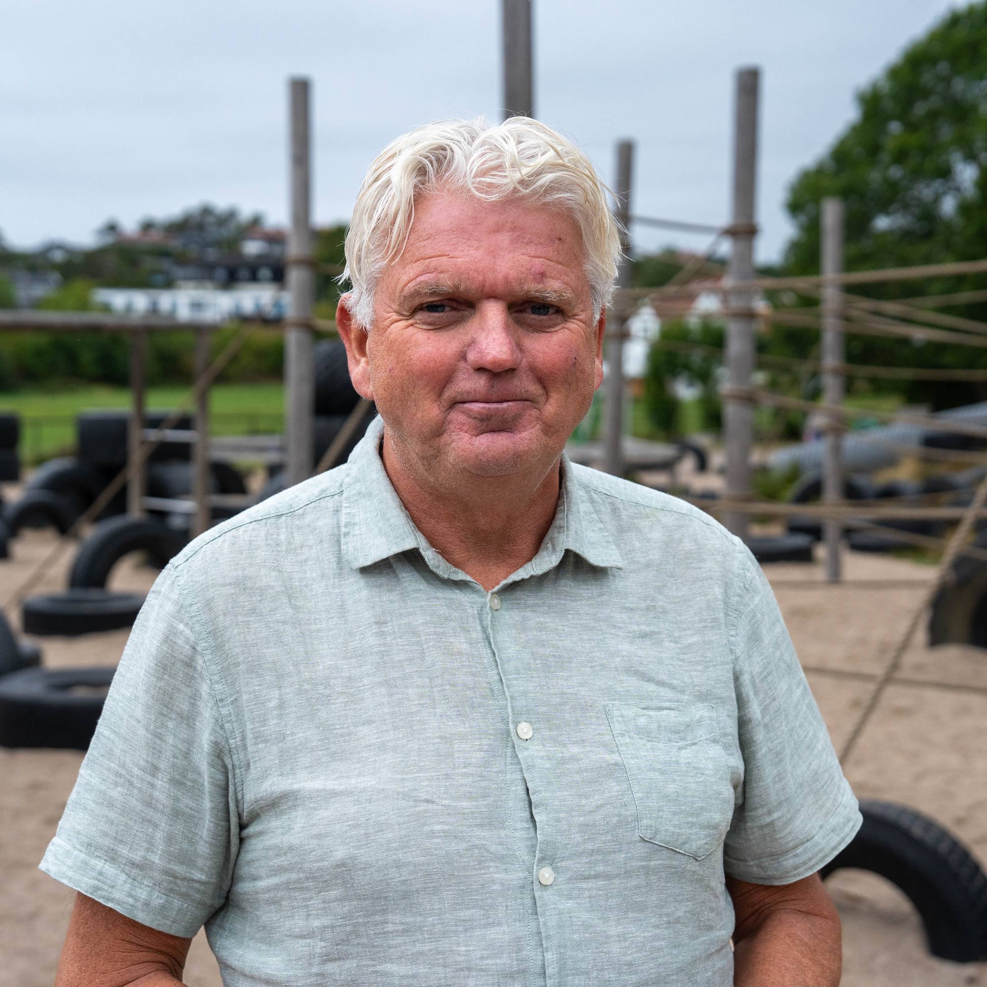 Øyvind Mosfjeld rektor Sjøstrand skole som står utenfor skolen, med lekestativer i bakgrunnen.