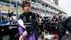Marco Bello / REUTERS,NTB En ung mann i Formel 1-drakt tar av seg jakken. Bak ham står et team med mekanikere og annet personell. En journalist filmer med videokamera. I bakgrunnen ser man tribuner med publikum og en pit lane. (Bildebeskrivelsen er laget av en KI-tjeneste)