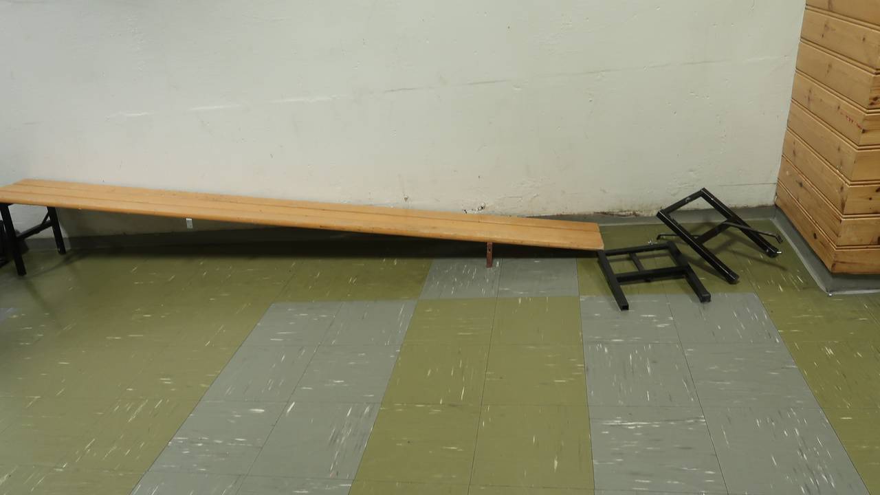 En benk står inntil en vegg, og beina i den ene enden er borte. Det gjør at benken er ubrukelig. 