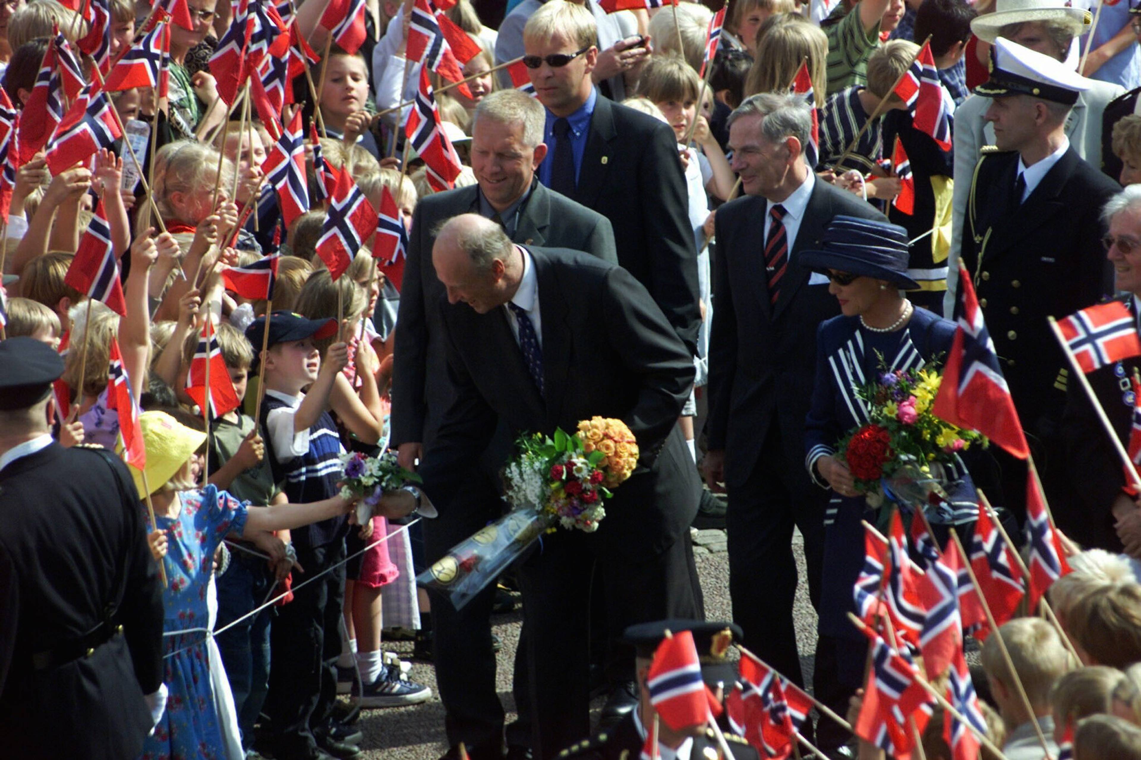 Kongeparet besøker Arendal. Tusenvis av tilskuerere hadde samlet seg i  Arendals gater for å hylle kongeparet da de besøkte byen tirsdag ettermiddag og kveld. Kongen mottar blomsterbuketter fra barn.