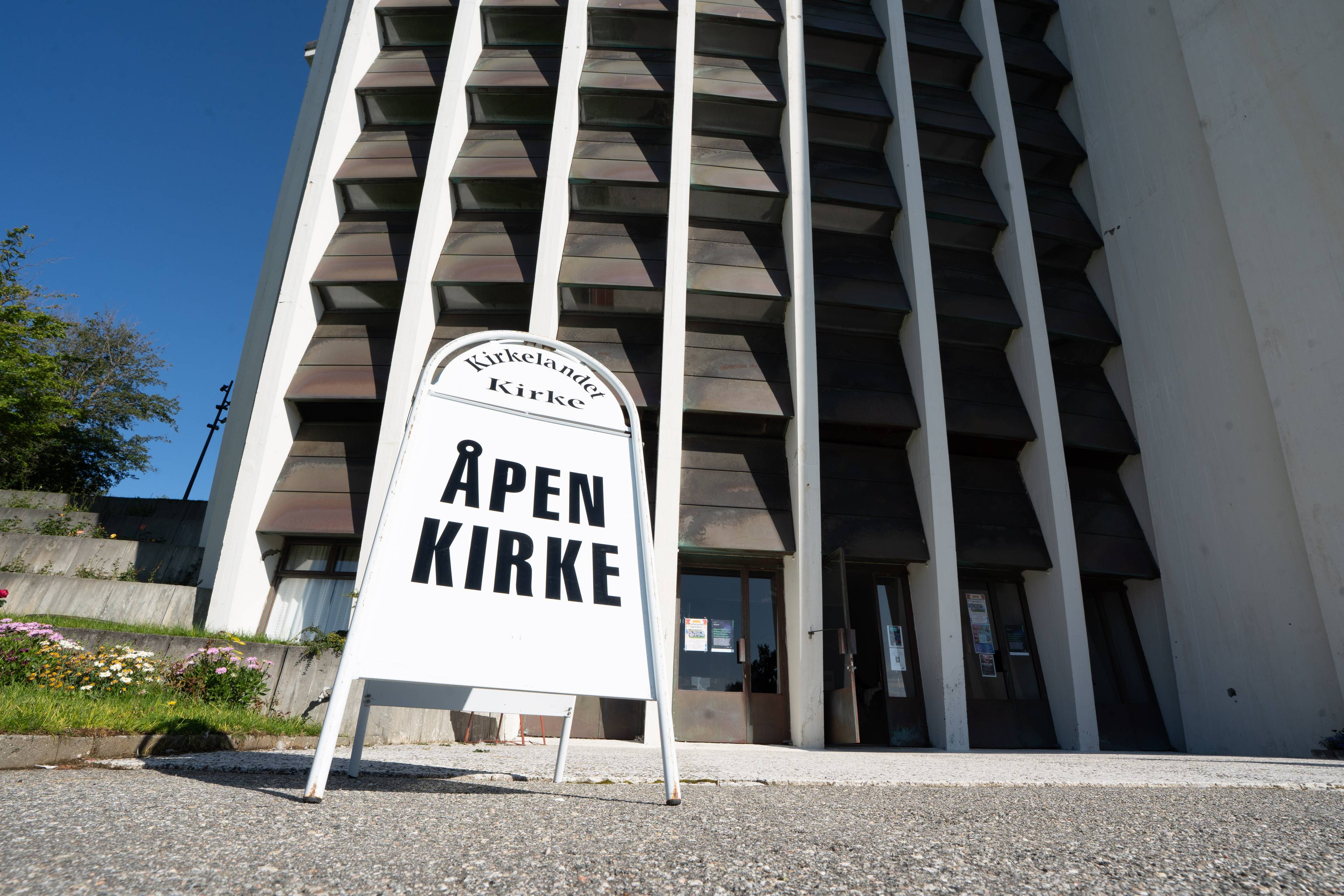 Skilt med teksten Åpen kirke foran inngangen til Kirkelandet kirke i Kristiansund. (Bildebeskrivelsen er laget av en KI-tjeneste)
