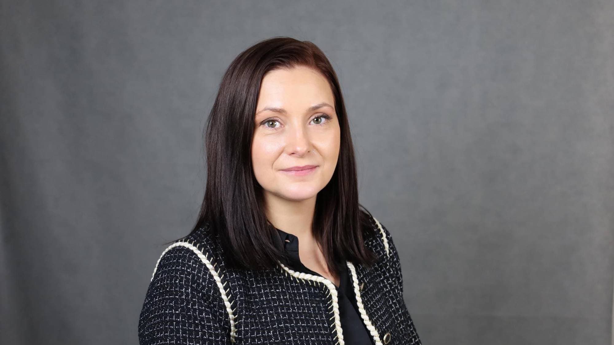 Direktør Yvonne Andersen ved Kontor for voldserstatning ser rett i kamera. Hun har brunt, rett hår til skuldrene og har på seg en jakke. Bak henne er en helt grå bakgrunn. 
