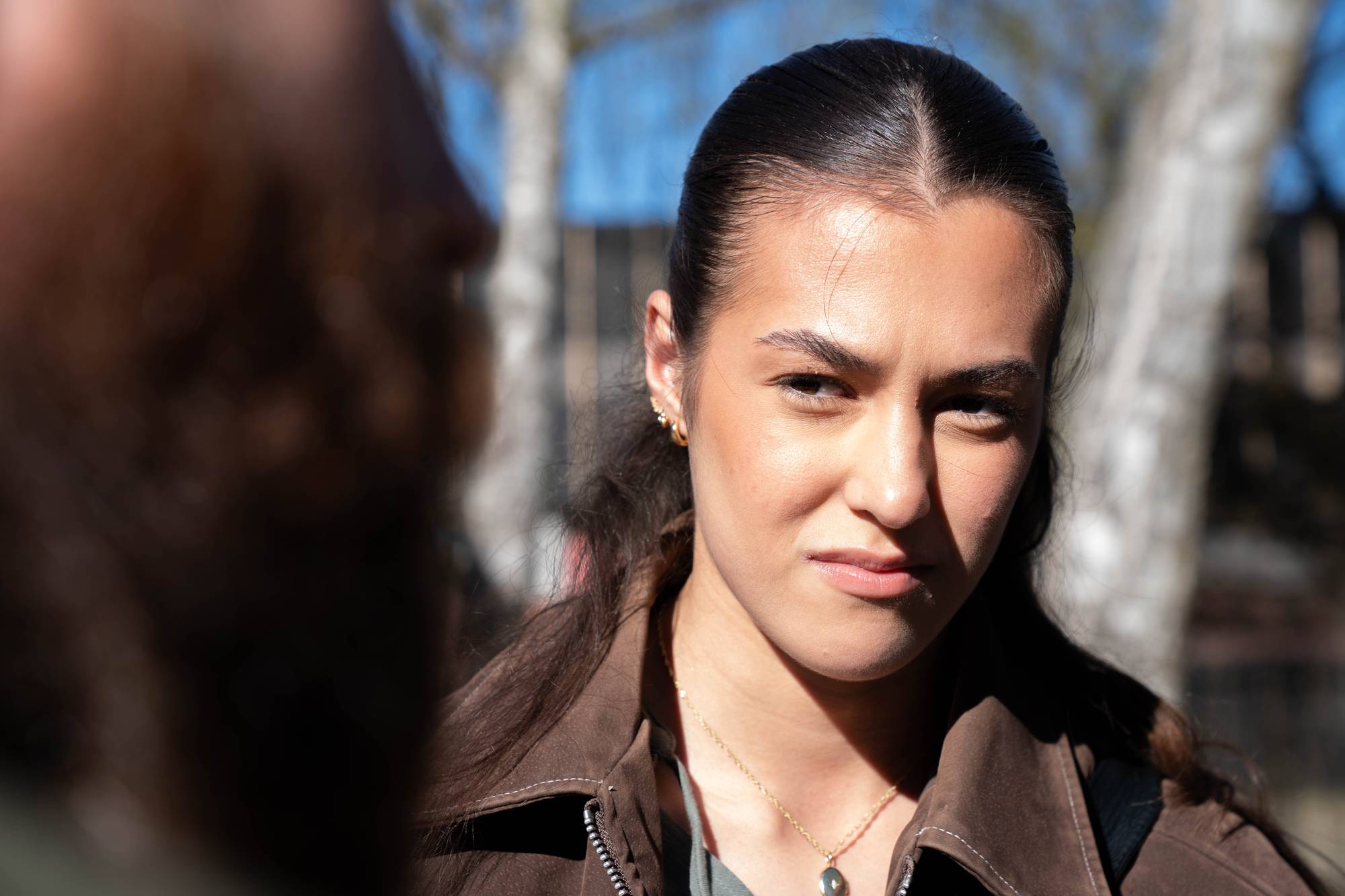 En ung kvinne med hestehale som kikker på reporteren med sol i ansiktet