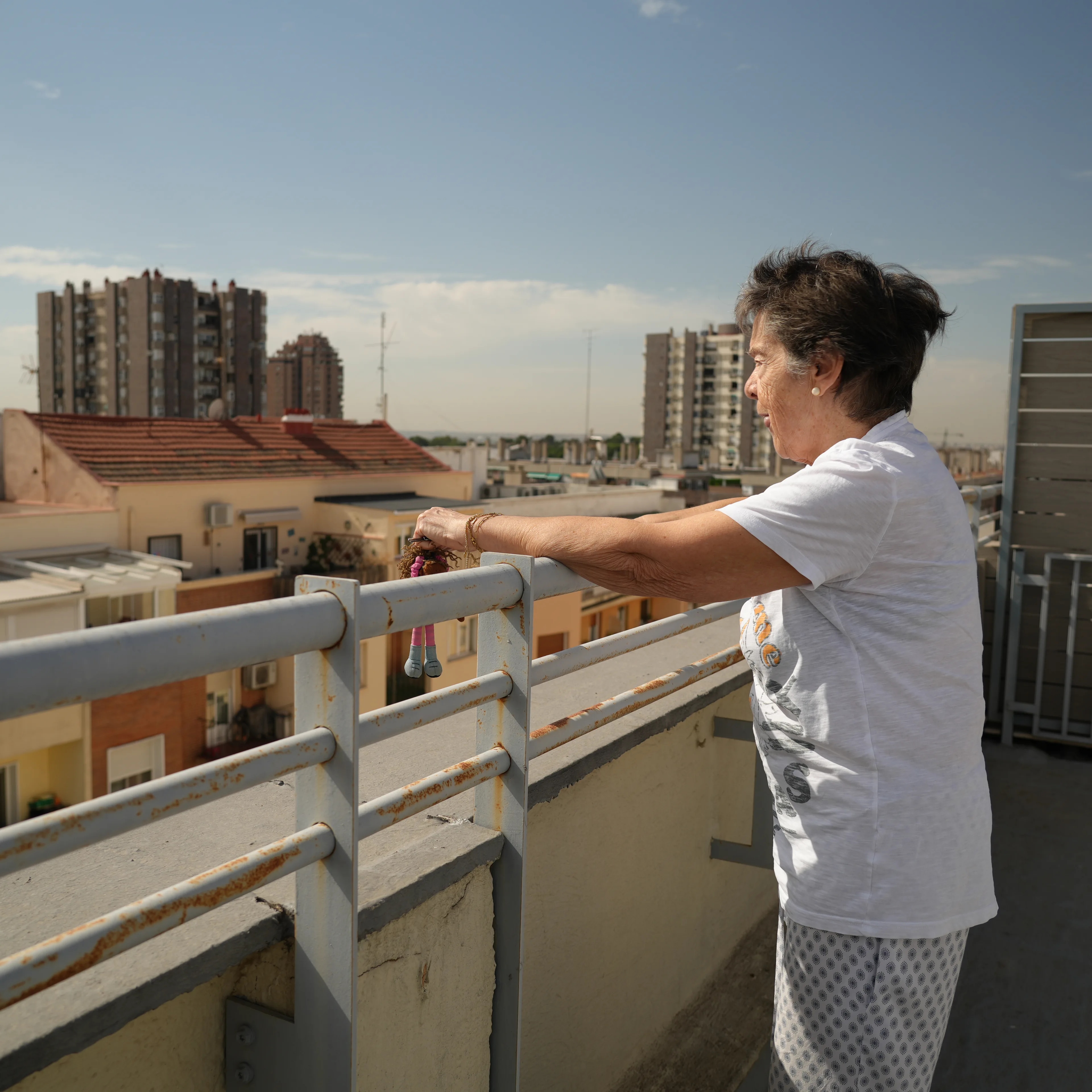 En kvinne står på en takterrasse og ser utover en by med leilighetsbygg. (Bildebeskrivelsen er laget av en KI-tjeneste)
