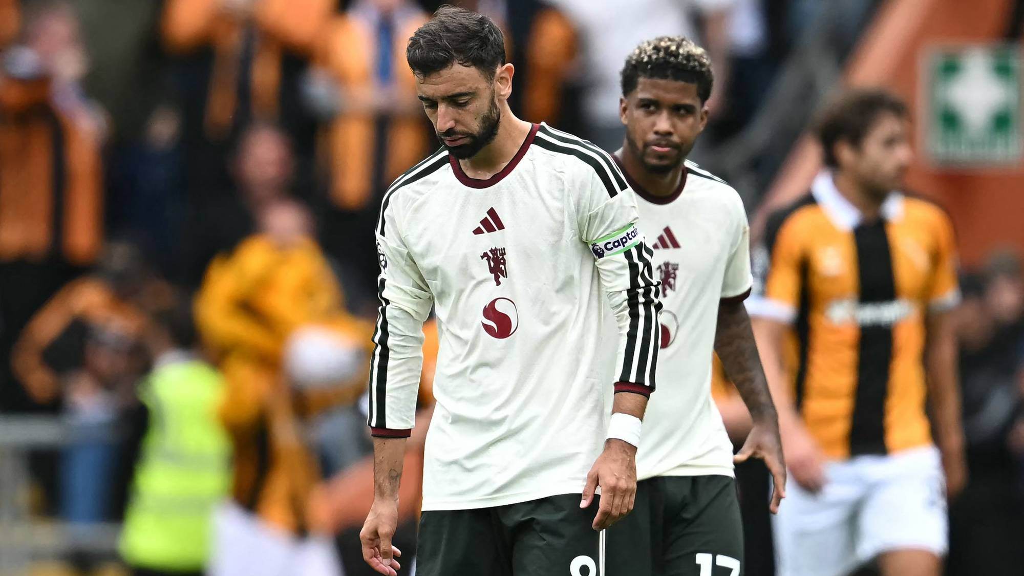 Bruno Fernandes og Andrey Santos går på fotballbanen med et nedslått uttrykk i hvite drakter. (Bildebeskrivelsen er laget av en KI-tjeneste)