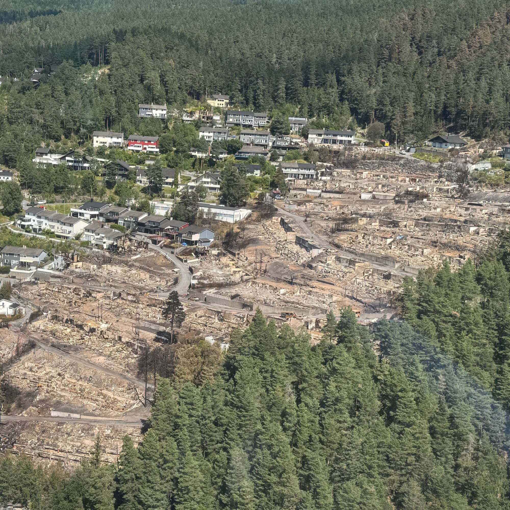 Flyfoto av et boligområde i Lærdal etter brannen, med mange utbrente hus tomter. 
