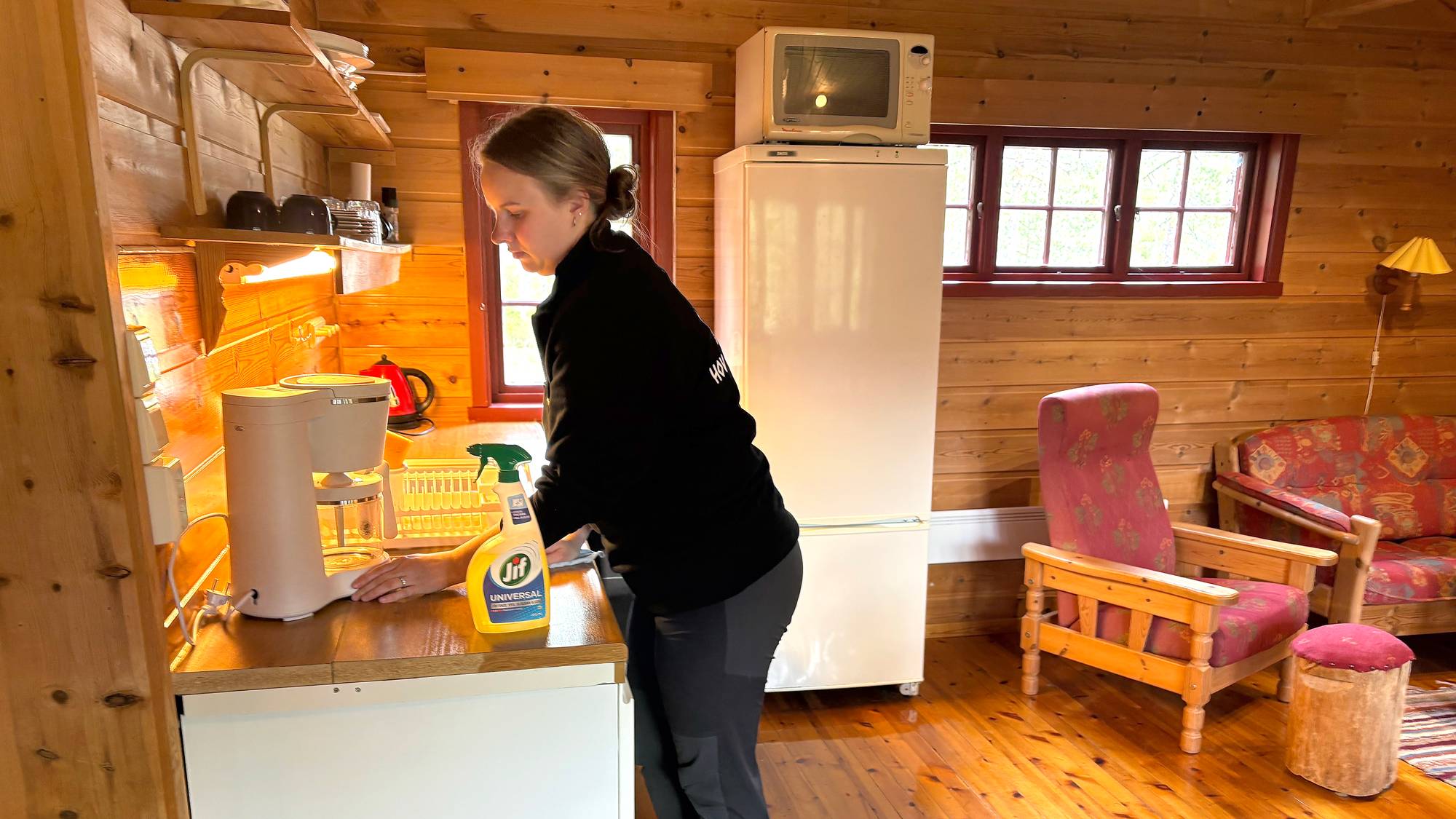 ei dame vaskar ein kjøkkenbenk i ei hytte 