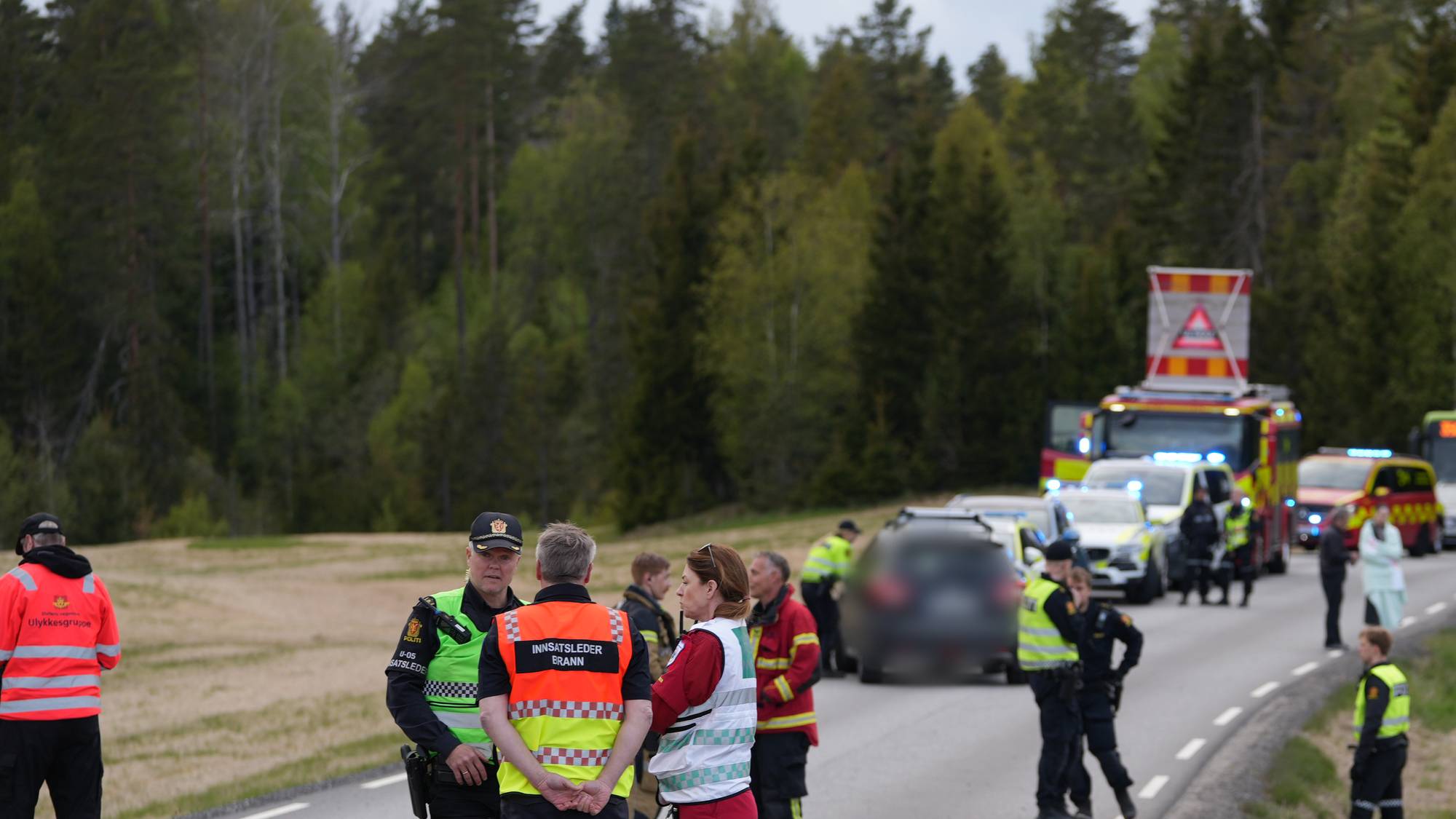 Ambulaser og redningsfolk langs en vei