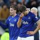 Scott Heppell / REUTERS,NTB To fotballspillere i blå drakter fra Everton står på en bane. En av spillerne holder seg til ansiktet med hånden, mens den andre ser ut mot siden. Begge spillerne har lagopper. Tilskuerne ses i bakgrunnen. (Bildebeskrivelsen er laget av en KI-tjeneste)