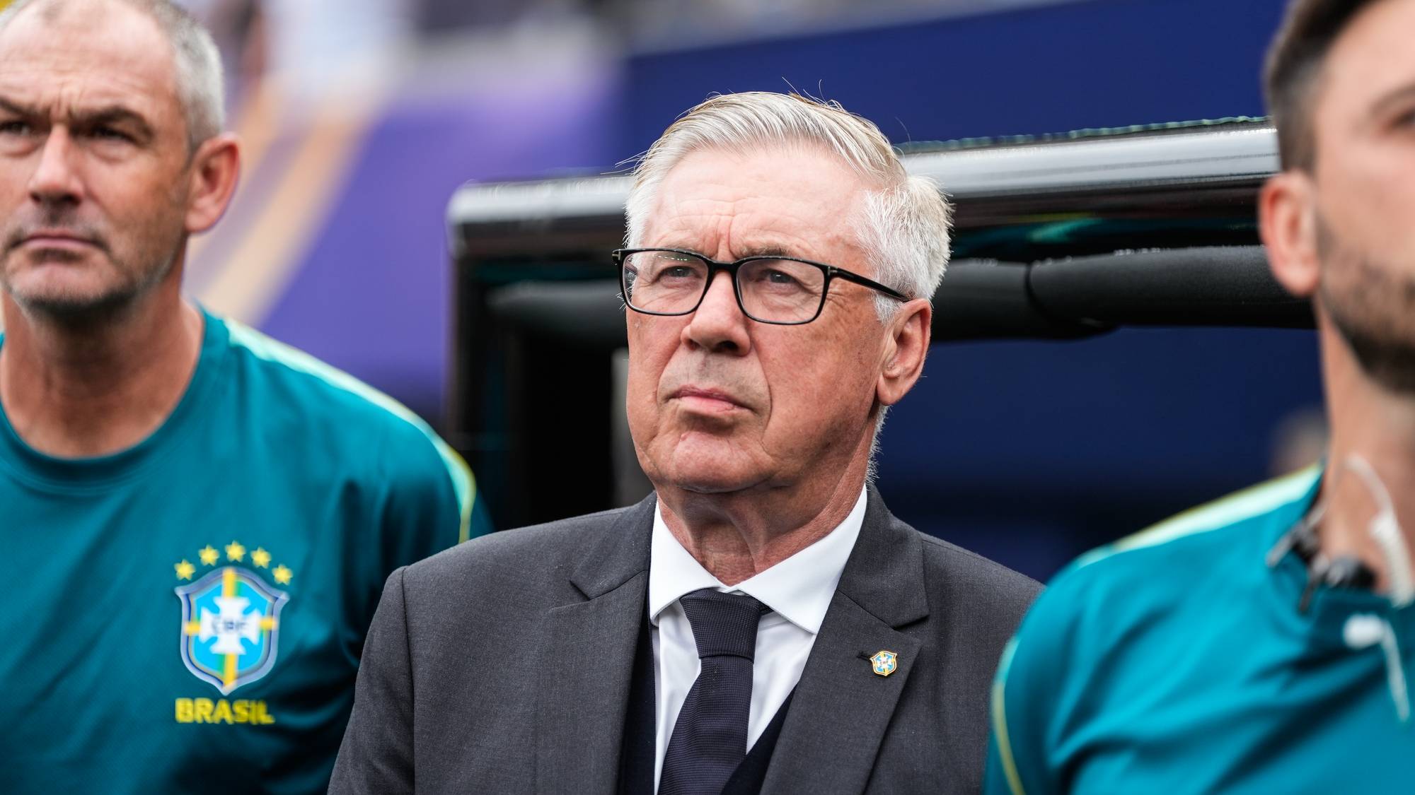 Carlo Ancelotti i dress ved siden av to personer i Brasils landslagstøy på sidelinjen. (Bildebeskrivelsen er laget av en KI-tjeneste)