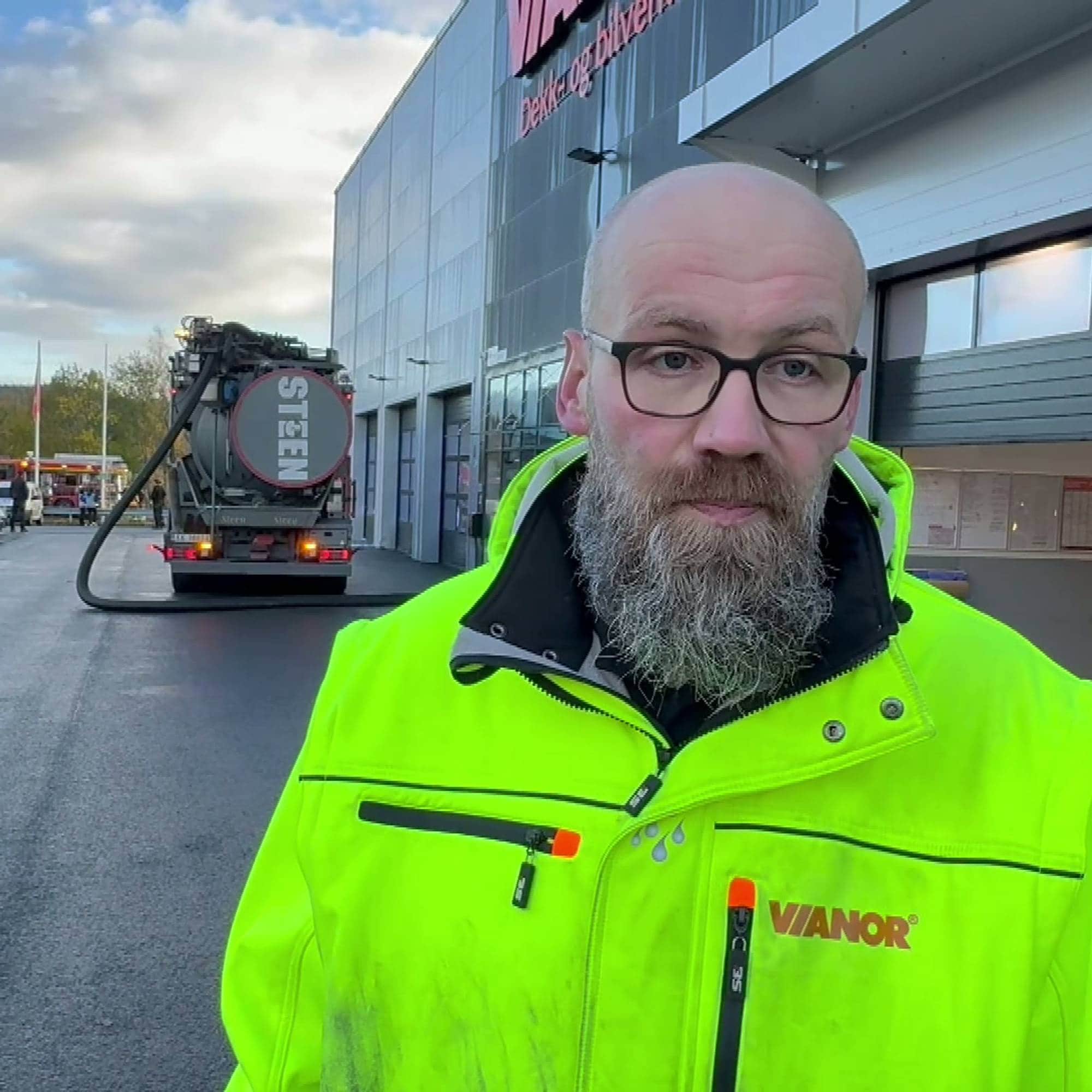 En mann i gul refleksjakke og briller