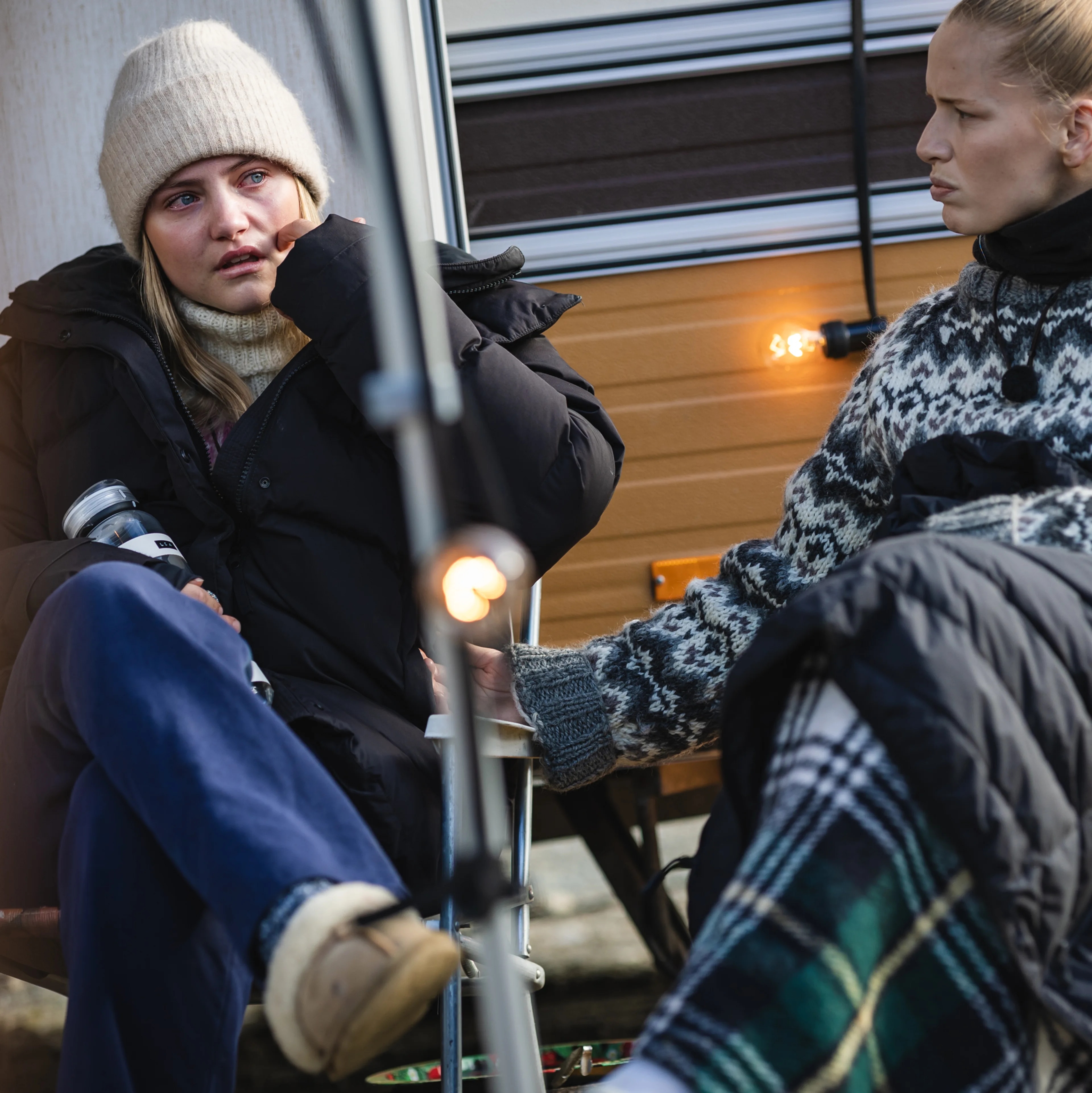 En ung dame sitter med tårer i øyene sammen med en annen kvinne.
