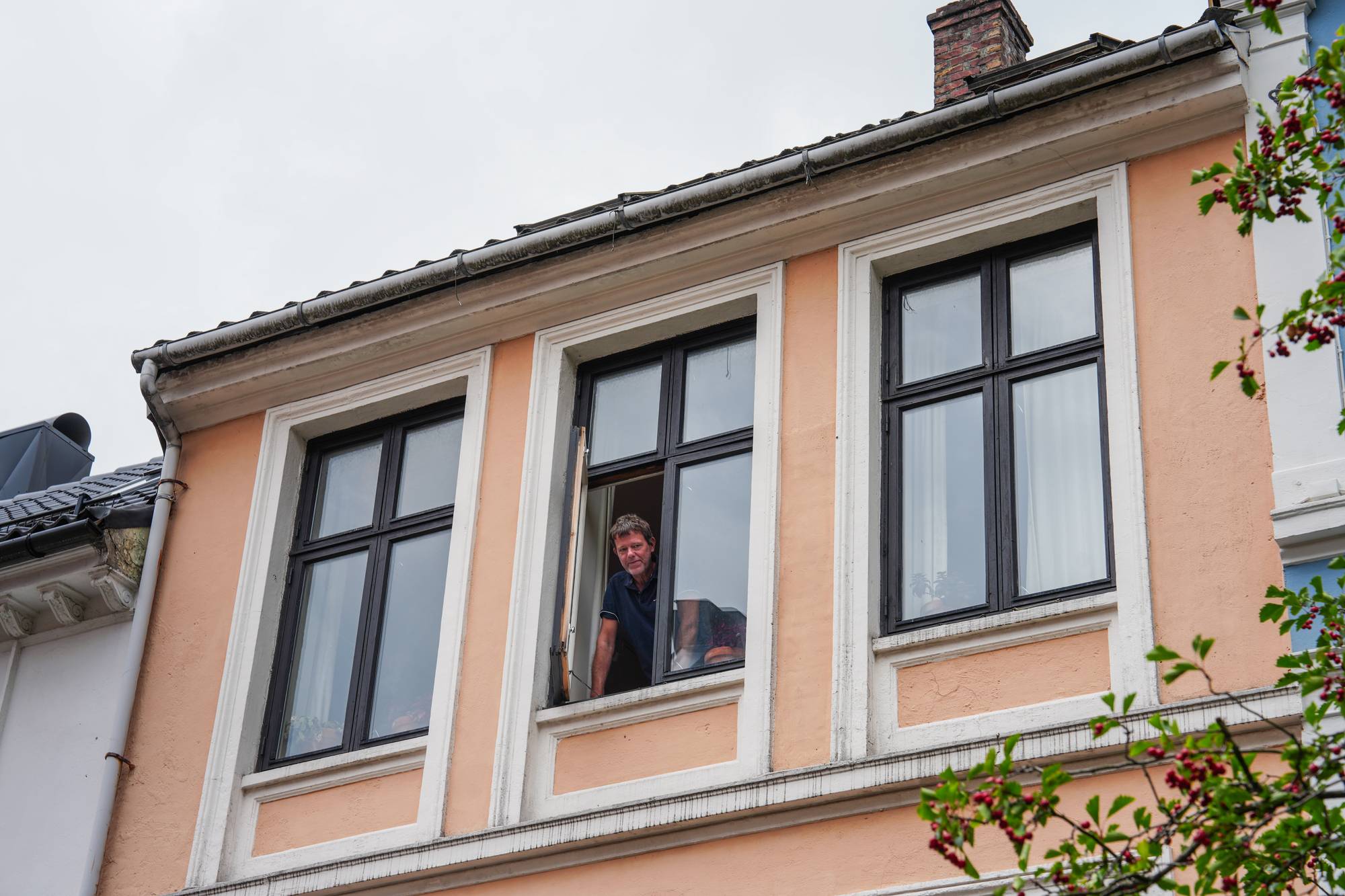 Mann ser ut av et vindu fra andre etasje 