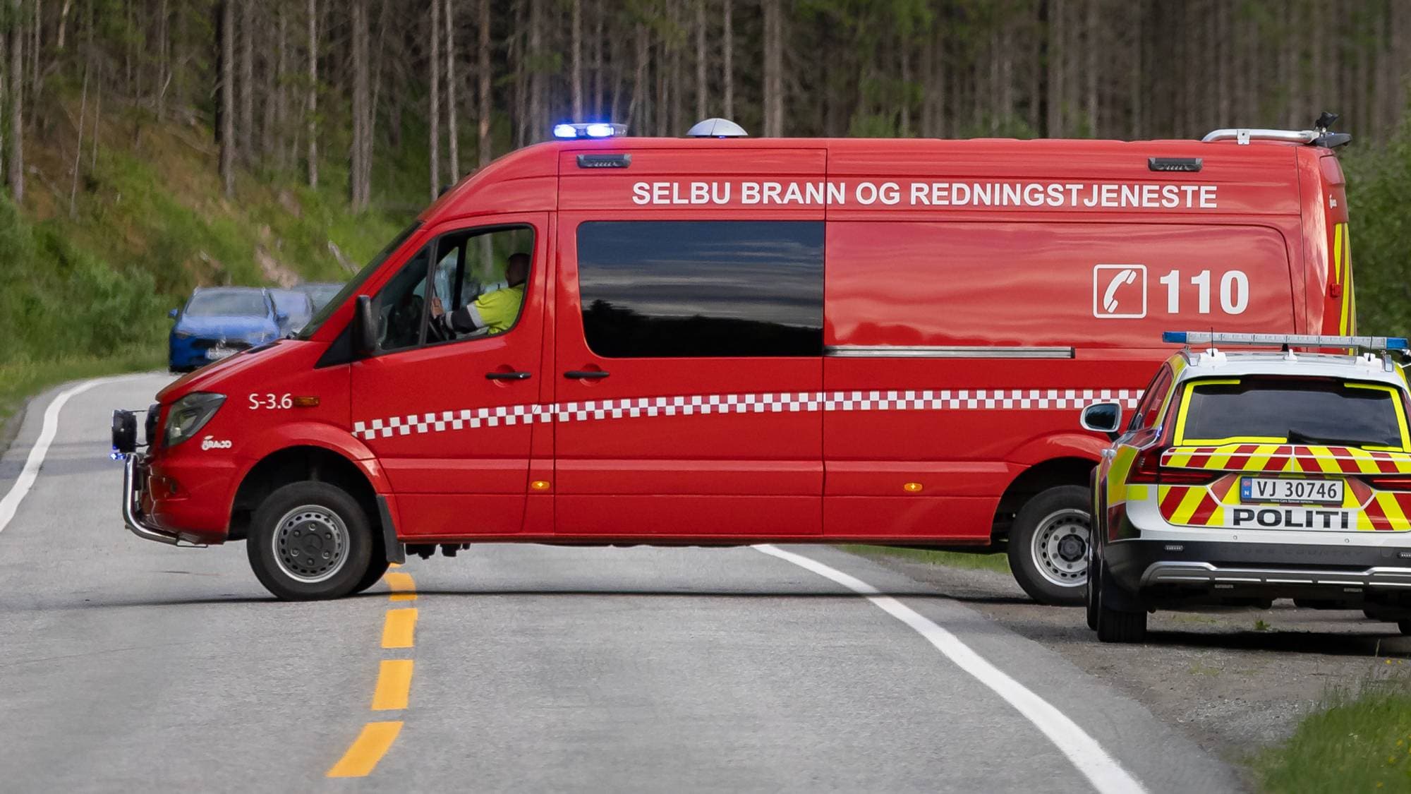 En mindre brannbil er i ferd med å rygge og snu på en vei. Vi ser også en politibil på stedet