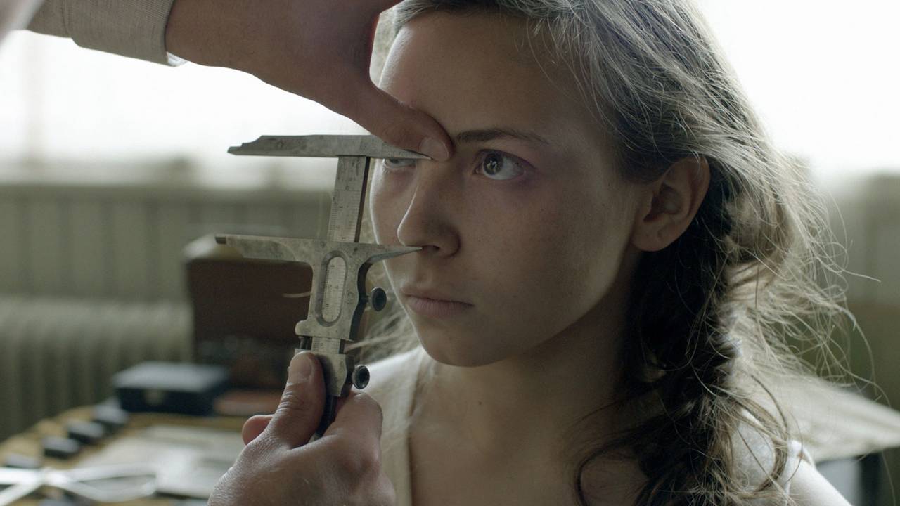 Lene Cecilia Sparrok i filmen Sameblod. Ung jente med fletter blir mål i ansiktet med et instrument.
