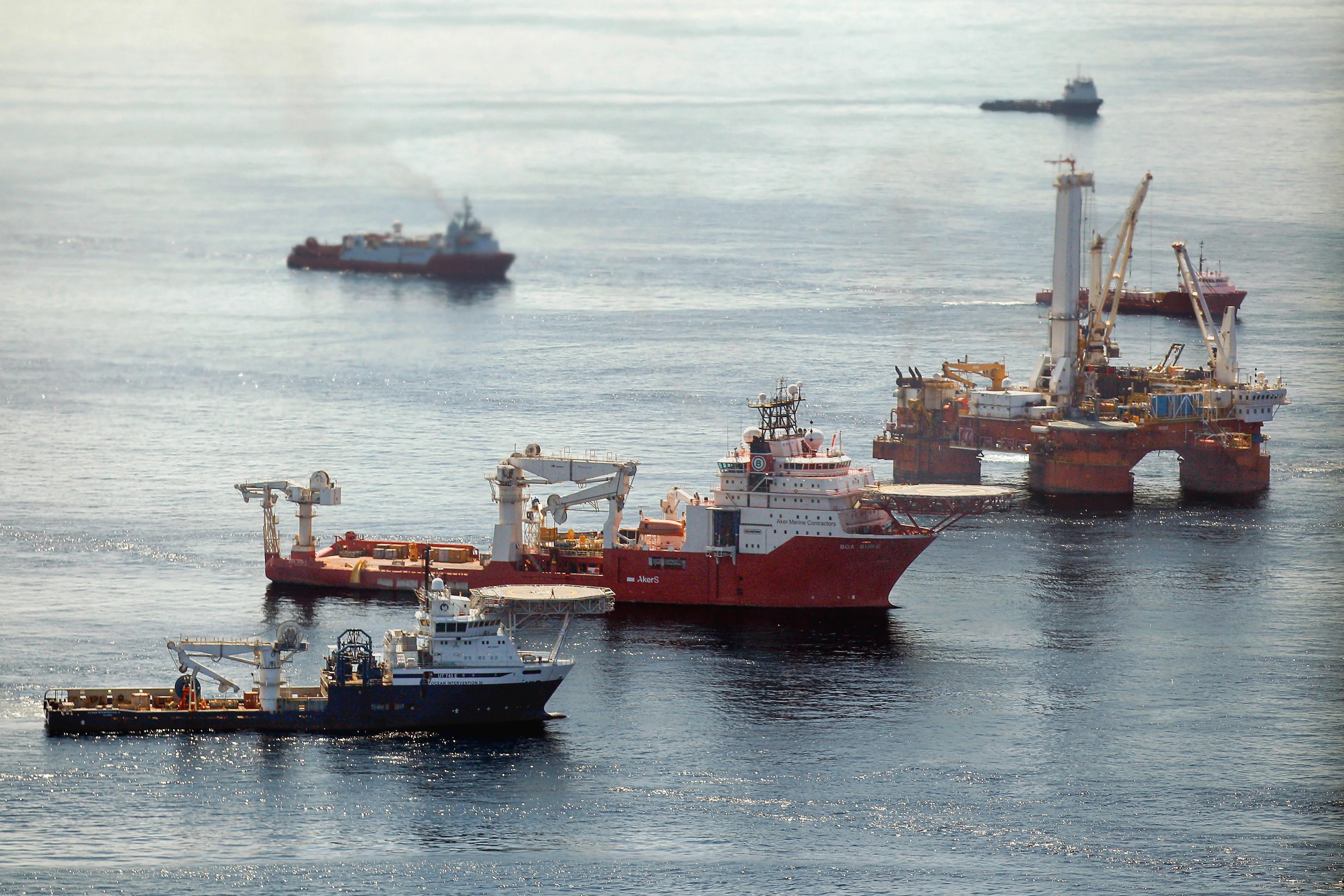 To norske offshore-båter og en oljerigg i havet.