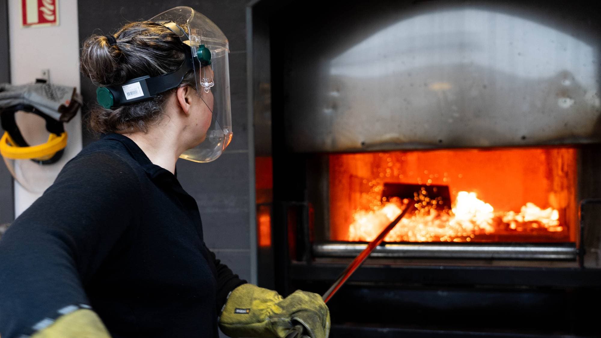 en person med maske og hansker som jobber på en fabrikk (Bildebeskrivelsen er laget av en KI-tjeneste)