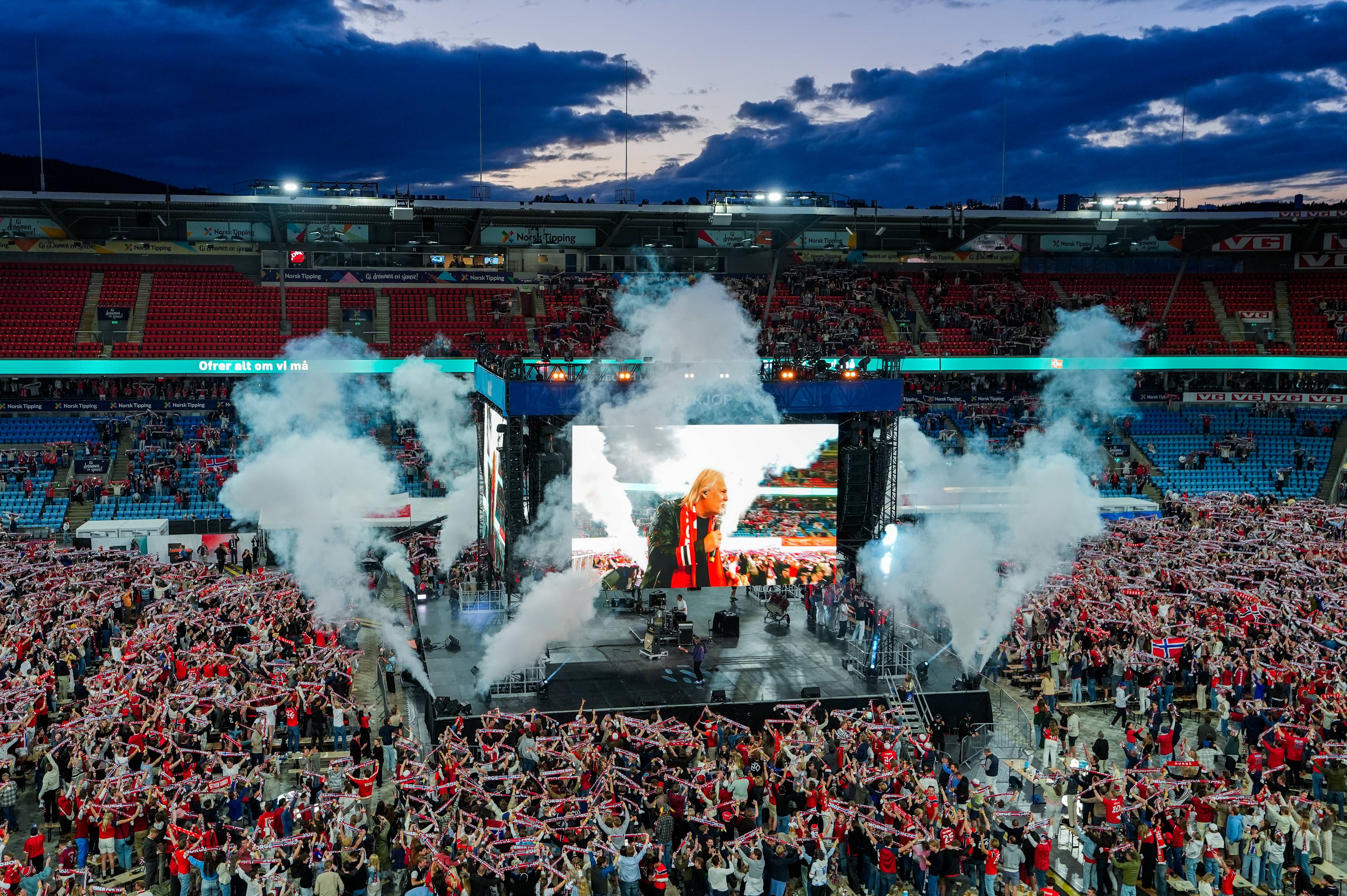 en folkemengde på stadion hvor det er satt opp enorm skjerm midt på gresset
