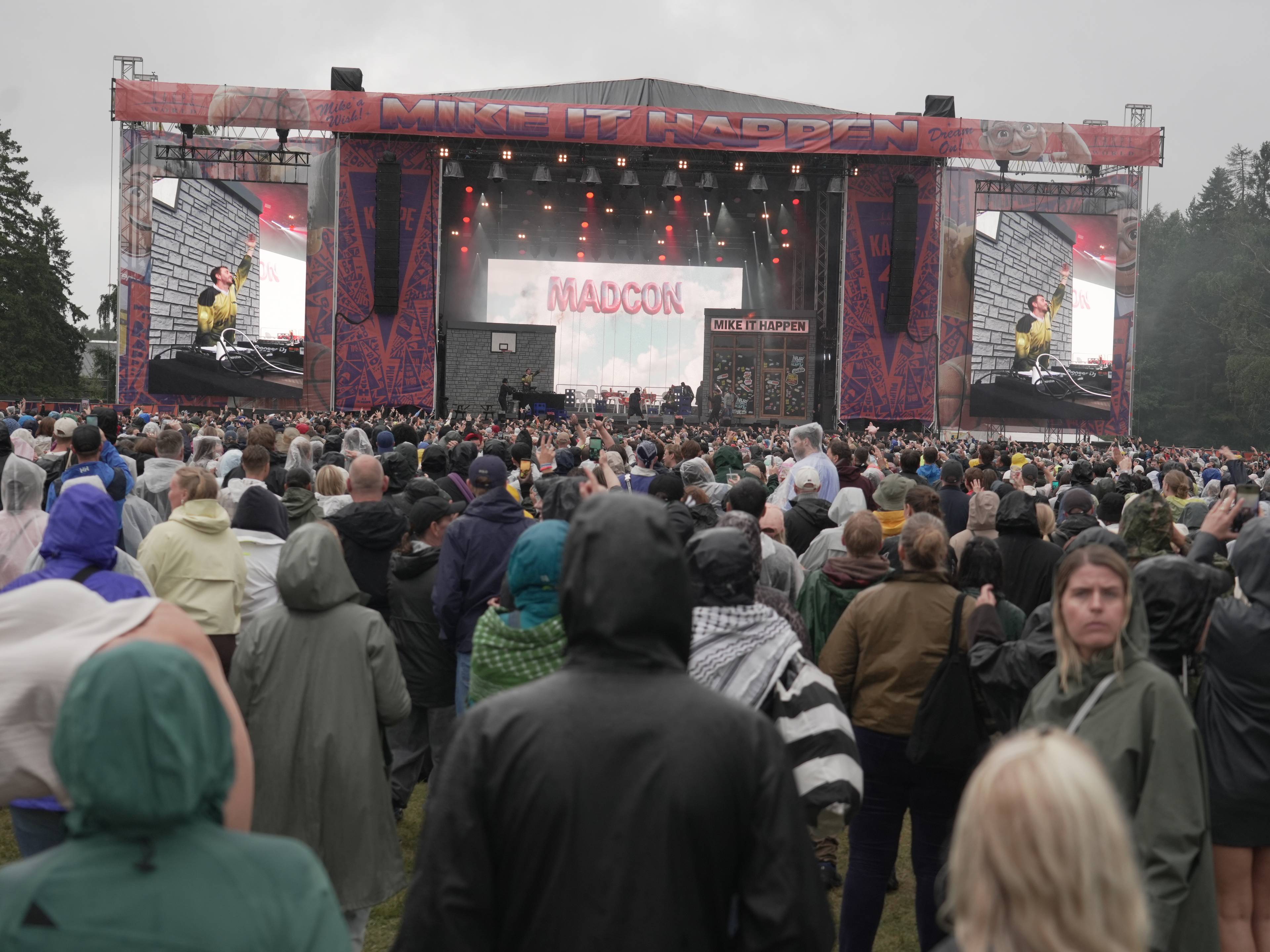 Publikum ser på konsert med Madcon fra en utendørs scene. Skjermer viser artister og bandnavn. (Bildebeskrivelsen er laget av en KI-tjeneste)