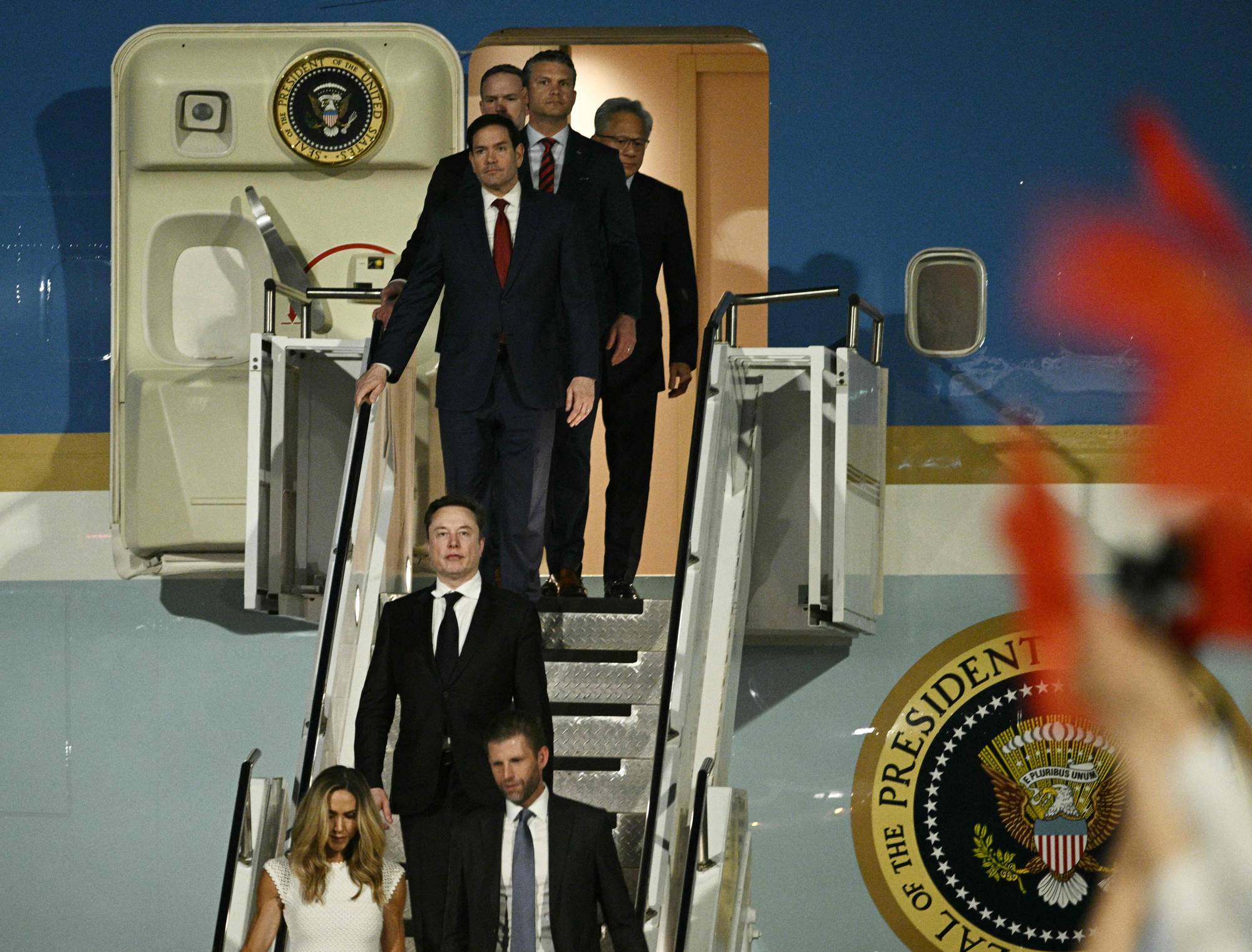 Menn i dress går ned trappen fra et fly. To kvinner og flere menn følger etter. Flyet har et President-segl på siden. (Bildebeskrivelsen er laget av en KI-tjeneste)
