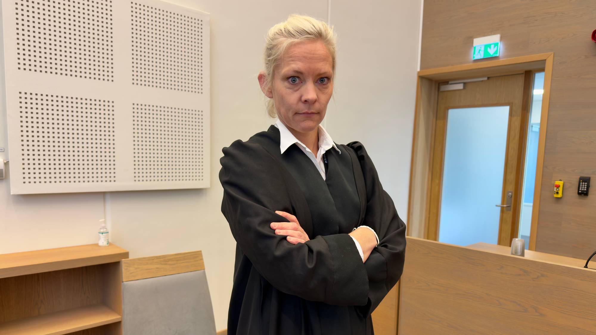 En kvinne står i retten med armene i kors.