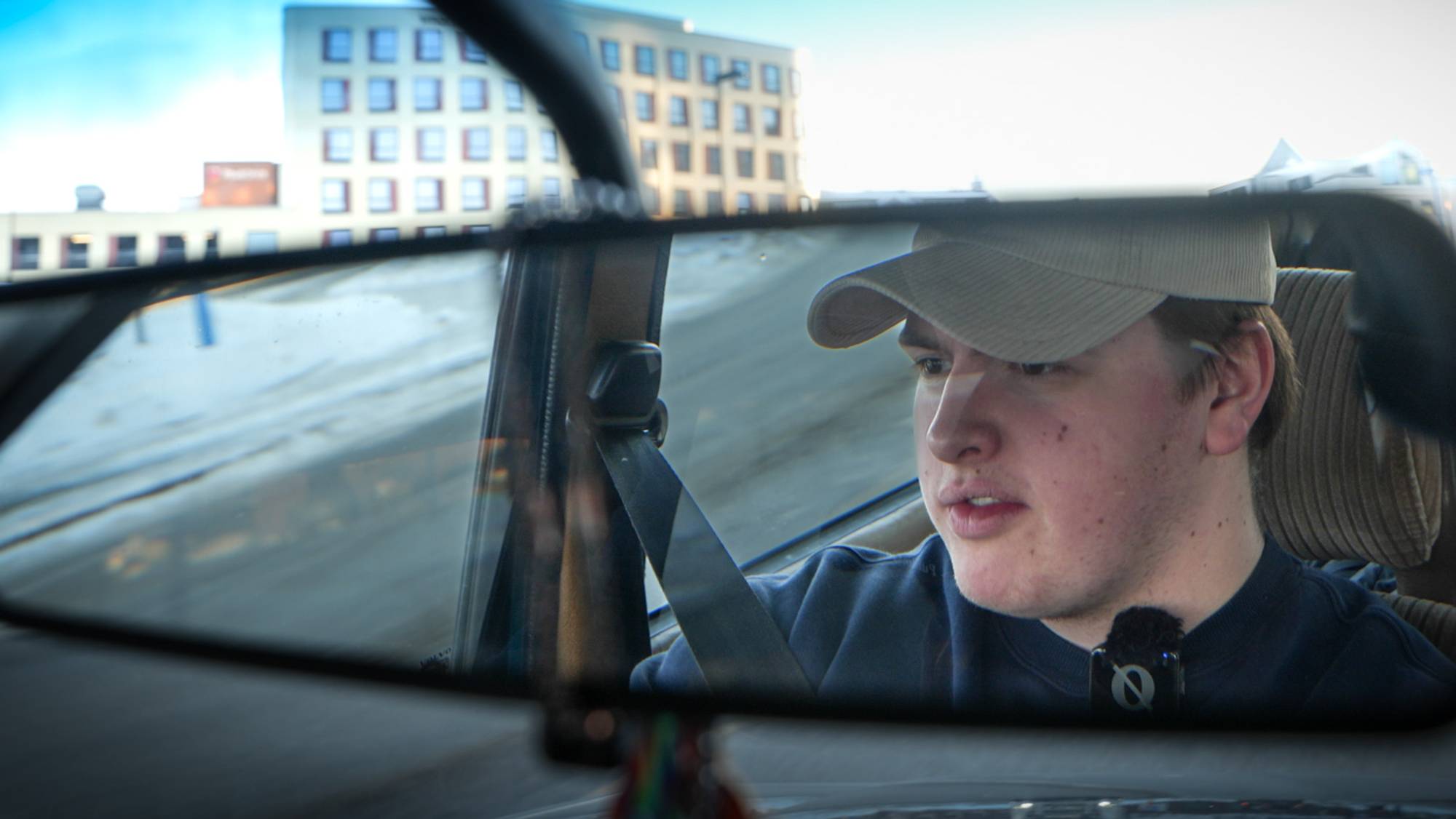 Ung mann, med mørkeblå genser og caps kjører Volvo 240