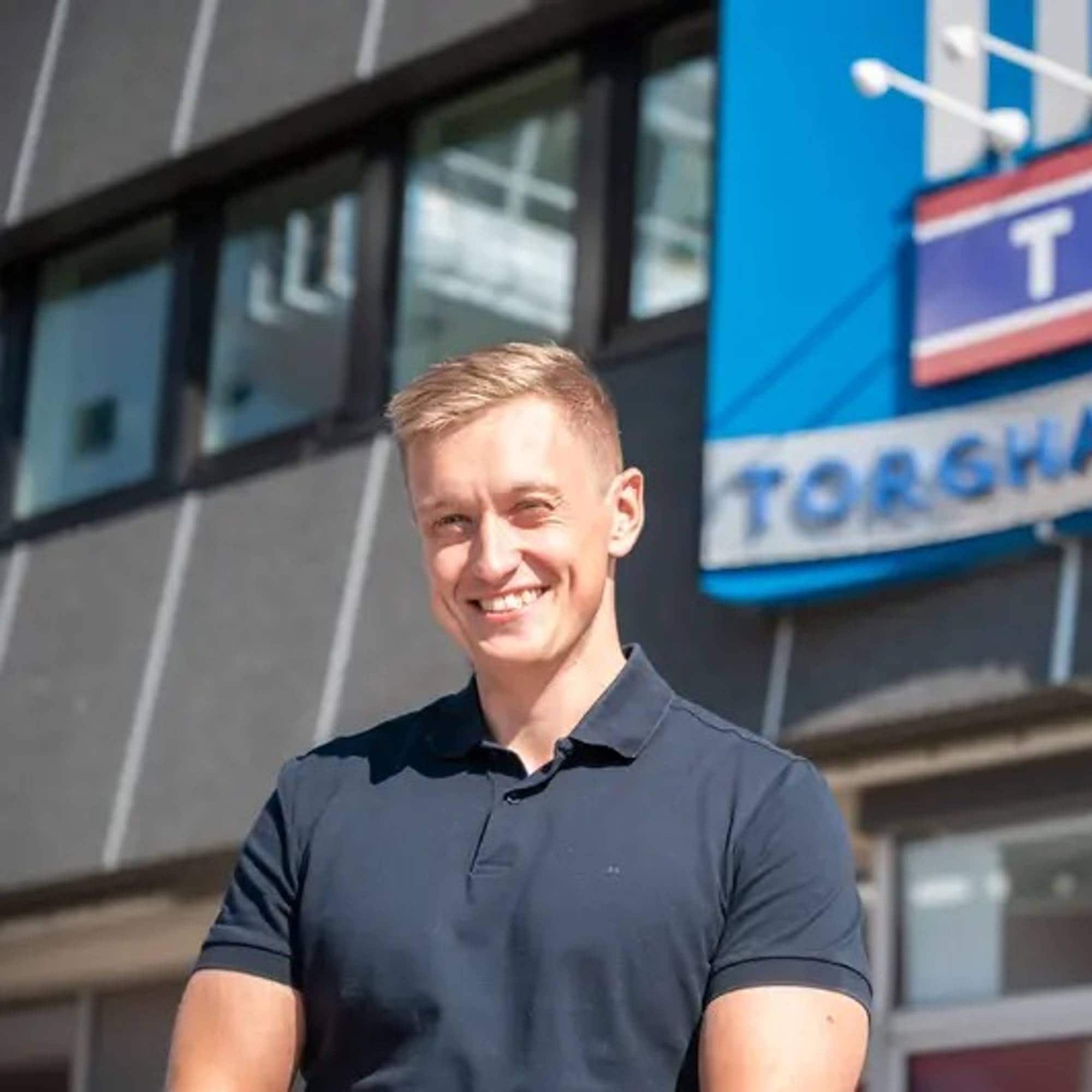 Mann som står foran inngangen til Torghatten og smiler i sollys