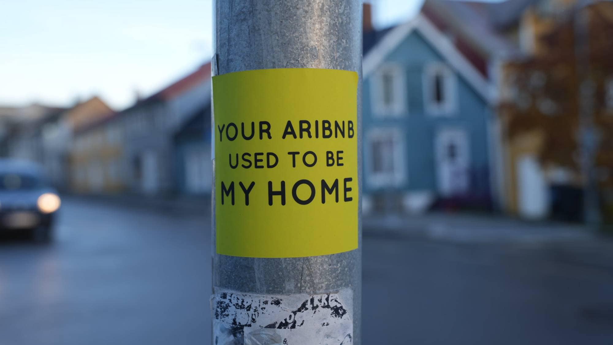 Et klistremerke på en stolpe med ordene: Din Airbnb pleide å være mitt hjem. 