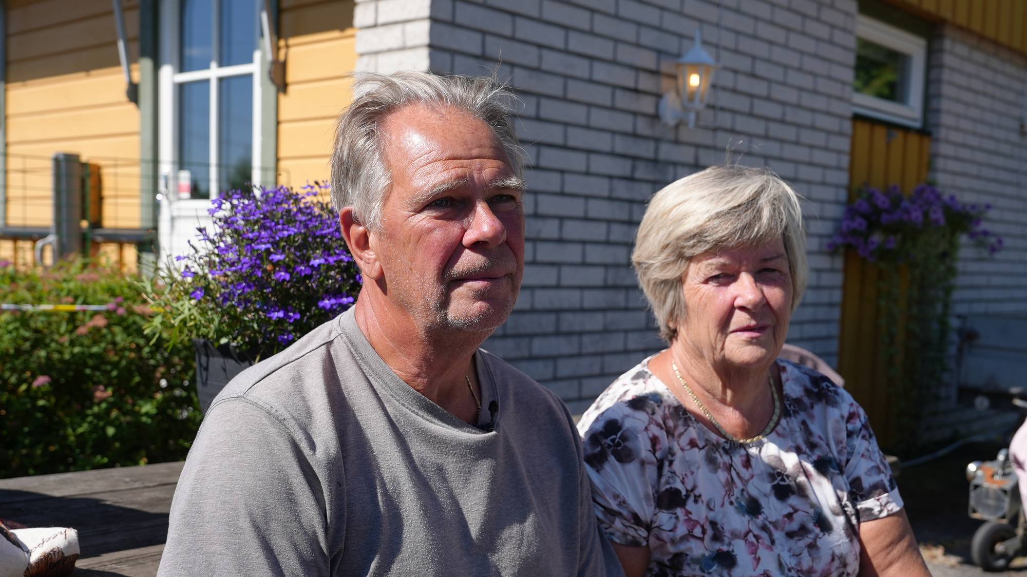 Huseier Paal og Grete. Paret sitter på en benk i solen. 
