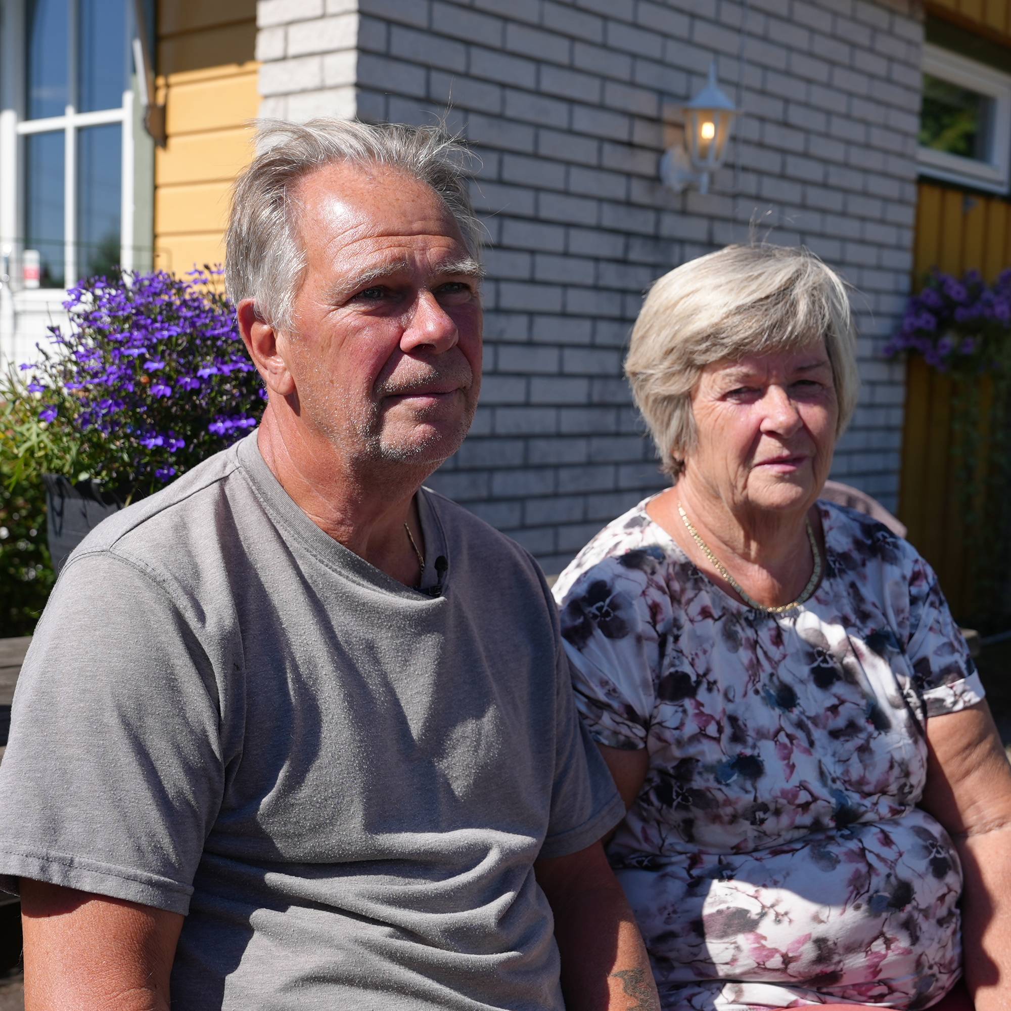 Huseier Paal og Grete. Paret sitter på en benk i solen. 