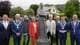 Foto: Eli Bjelland / NRK Åtte personer står samlet foran en statue utendørs. Alle unntatt én kvinne har på seg dress og har et kjede over jakken. Kvinnen har på seg en oransje dress. Været er overskyet og flere personer i bakgrunnen holder paraplyer. (Bildebeskrivelsen er laget av en KI-tjeneste)
