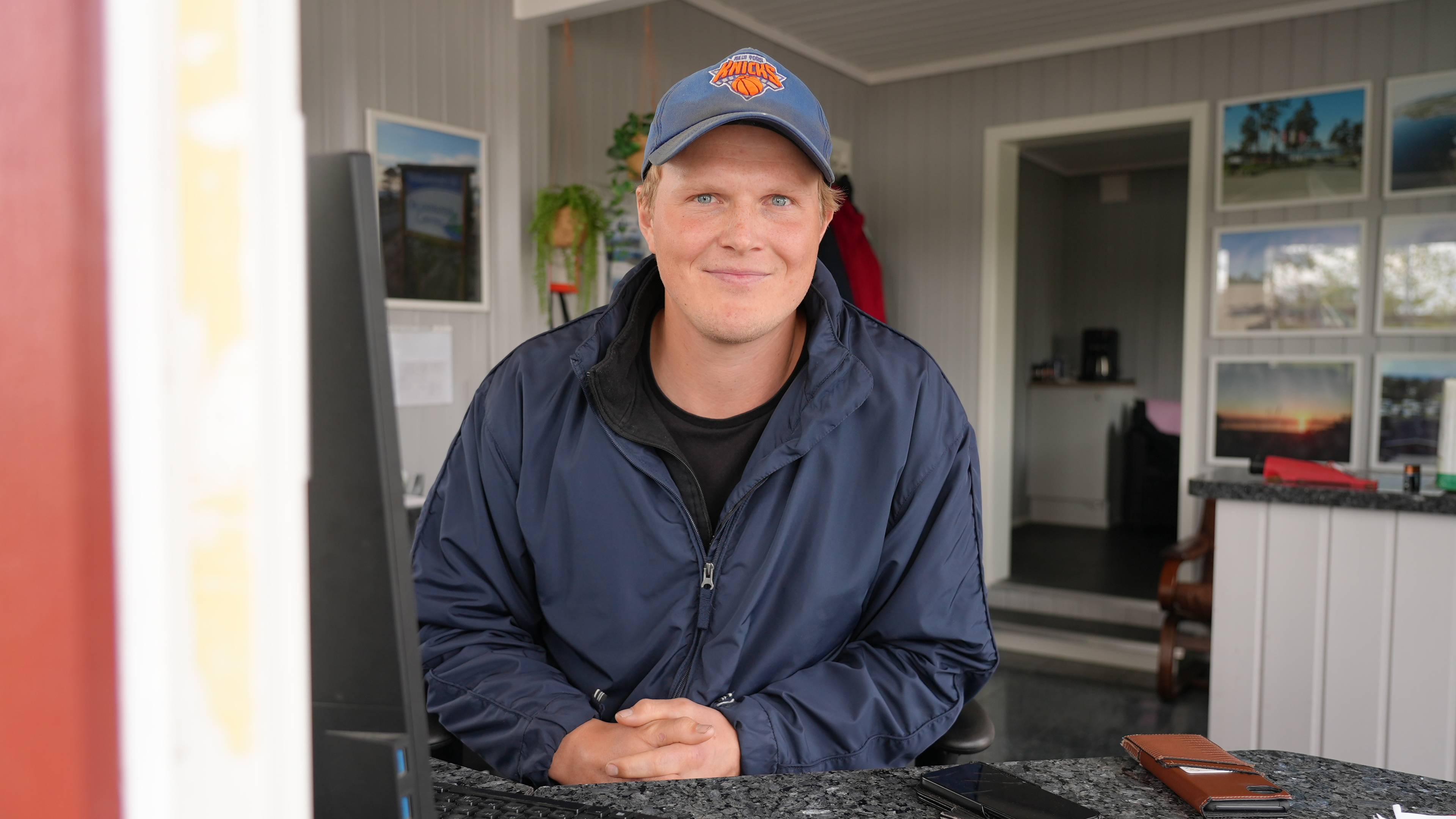Hans Omlid ser i kamera, han sitter bak en pult med pc.