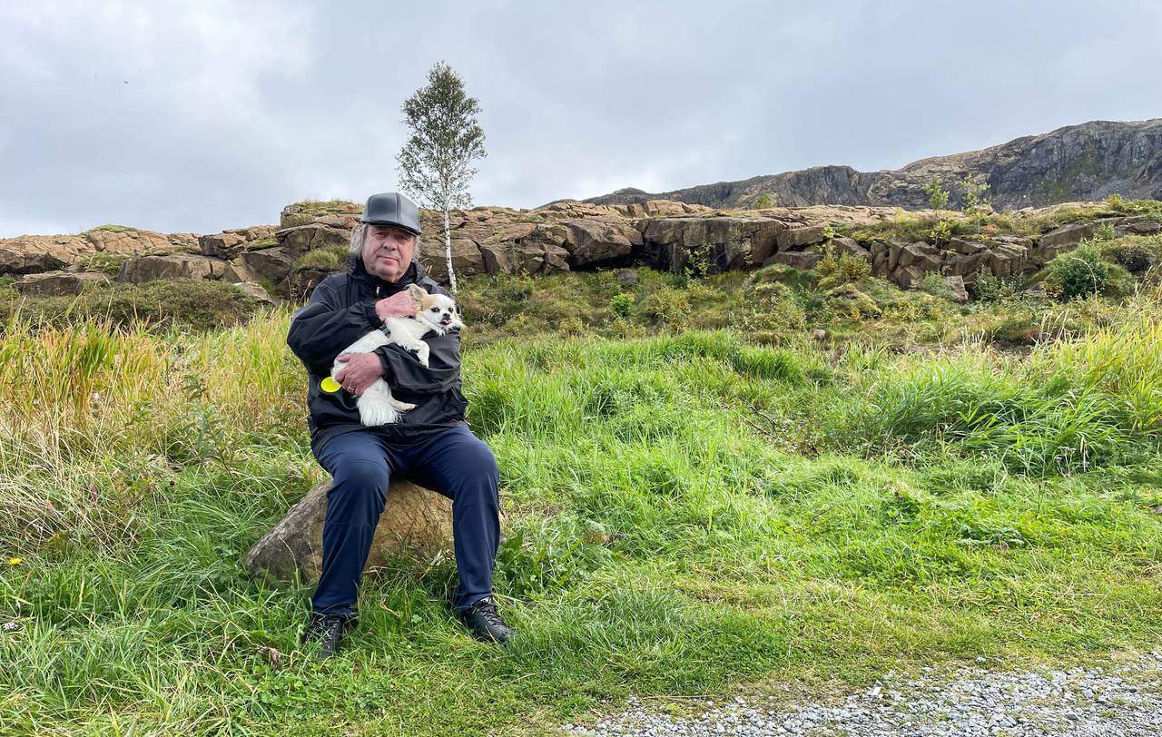 Bjørn Sigurd Larsen sitter på en stein med chihuahuaen Odin i armene.